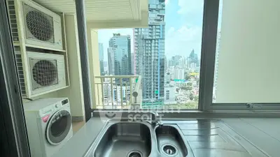 Modern kitchen with city view, featuring stainless steel sink and washing machine, perfect for urban living.