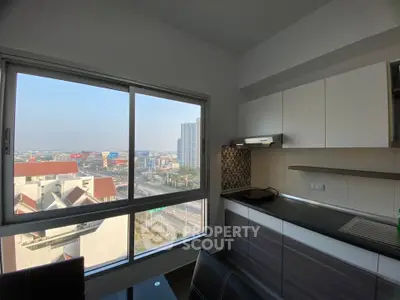 Modern kitchen with city view, sleek cabinets, and ample natural light.