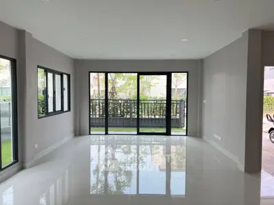 Spacious modern living room with large windows and glossy floors, offering a serene garden view.