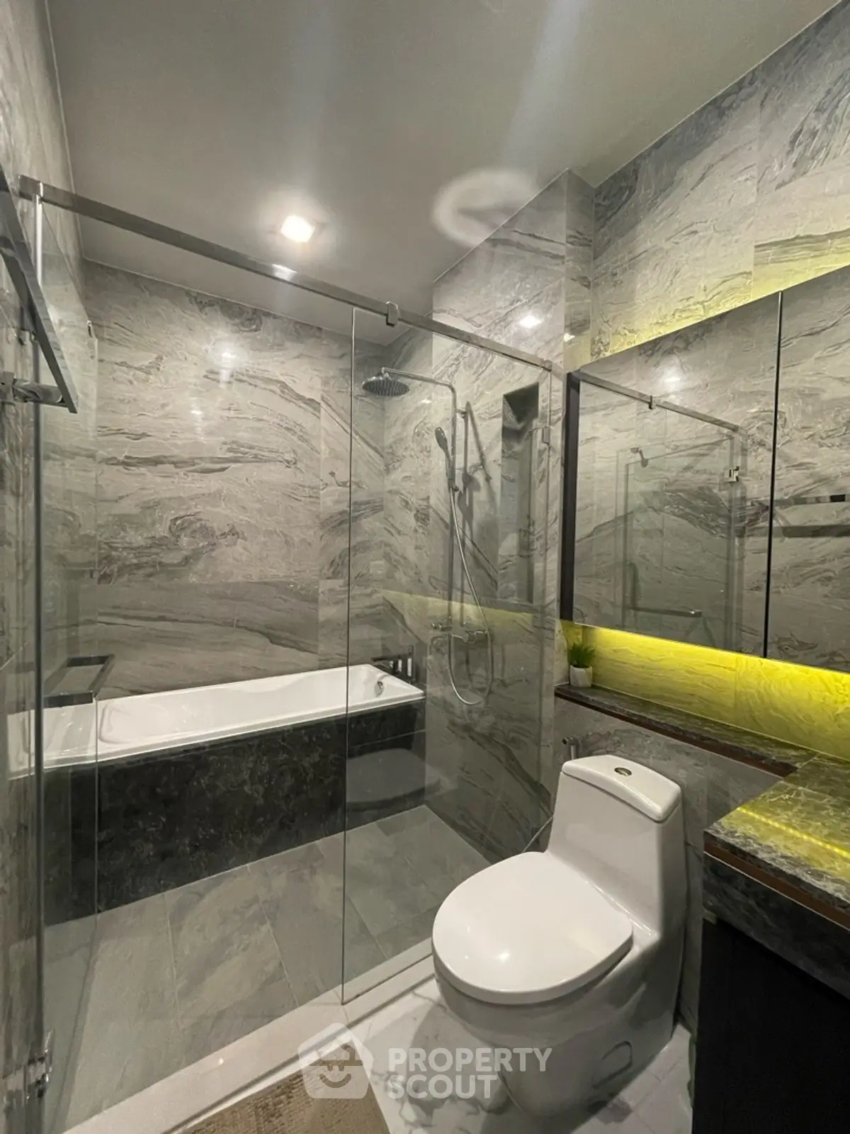 Luxurious modern bathroom with marble tiles and glass shower enclosure.