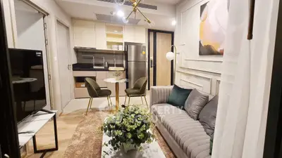 Modern living room with stylish decor and open kitchen layout, featuring a cozy sofa and elegant dining area.