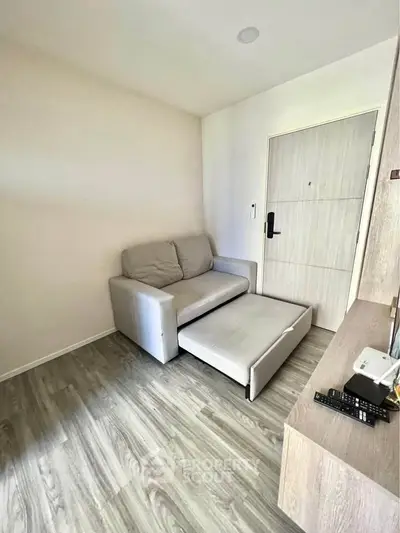 Cozy living room with modern sofa bed and wooden flooring, ideal for compact spaces.