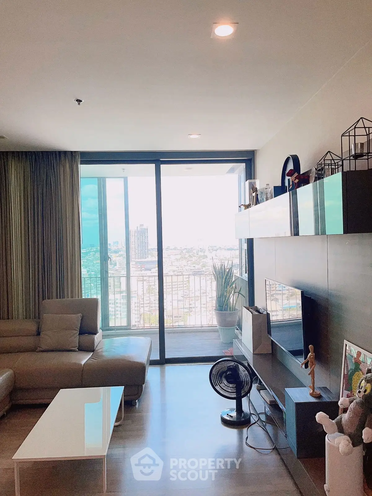 Spacious living room with modern decor and city view balcony in high-rise apartment.