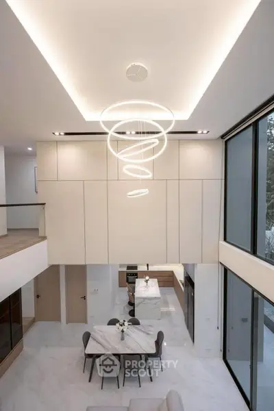 Modern open-plan living room with high ceiling and elegant lighting