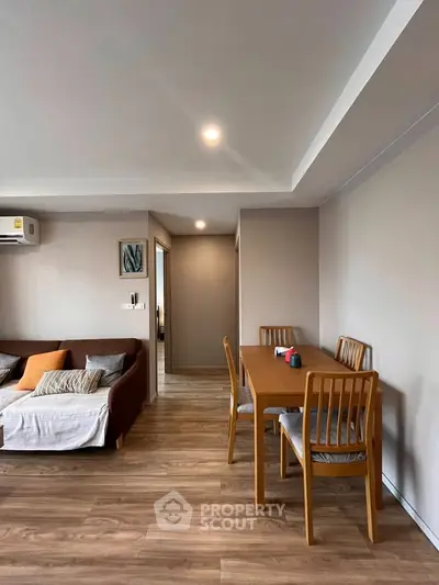 Spacious living room with modern furniture and wooden flooring in a cozy apartment.