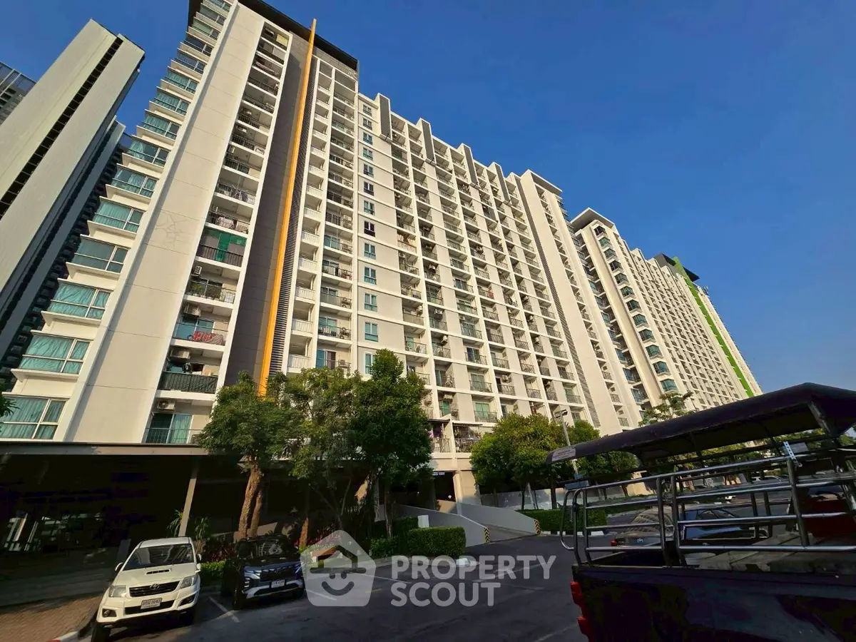 Modern high-rise apartment building with spacious balconies and ample parking space.