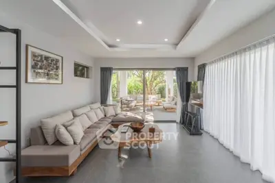 Spacious modern living room with large windows and garden view, featuring stylish furniture and natural light.