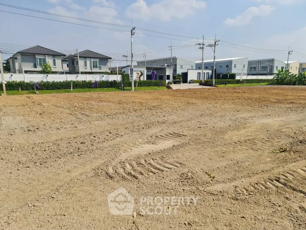 Prime residential land for sale with modern houses in the background, ideal for new development.