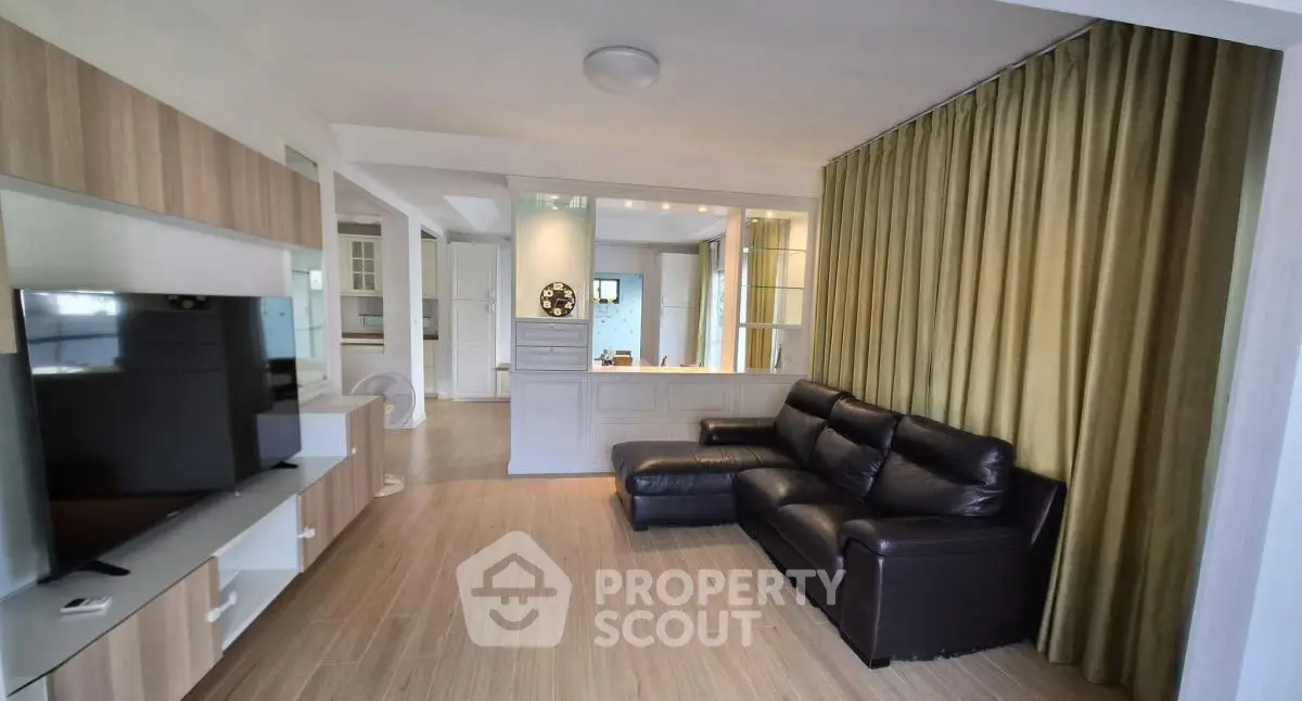 Spacious living room with modern decor and large TV, perfect for relaxation and entertainment.