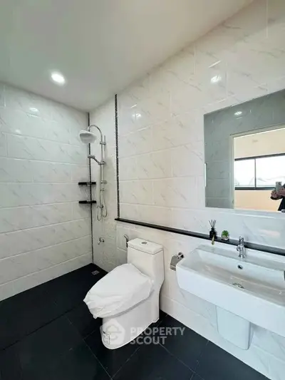Modern bathroom with sleek design, featuring a spacious shower and elegant fixtures.