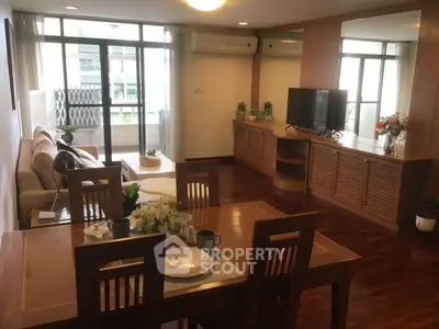 Spacious living room with elegant wooden flooring and modern decor, featuring a cozy dining area and large windows.