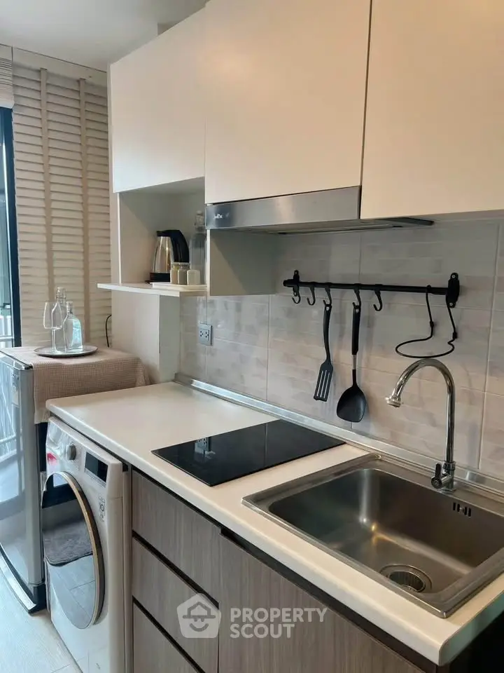 Modern kitchen with sleek appliances and washing machine, perfect for urban living.