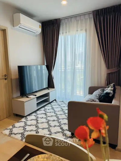 Modern living room with large TV, cozy sofa, and elegant curtains in a bright apartment.