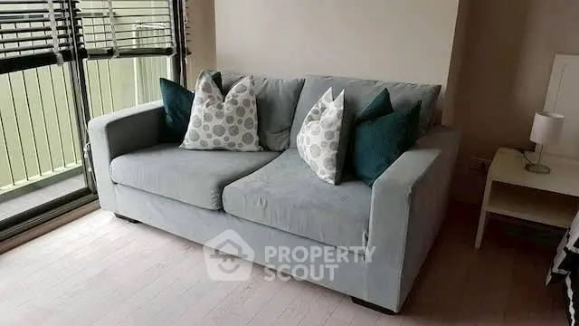 Cozy living room with stylish gray sofa and decorative pillows near large window.