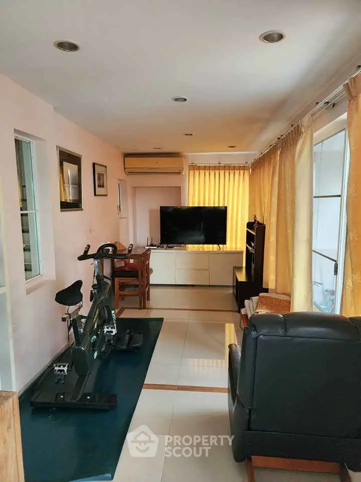 Cozy living room with exercise bike and modern TV setup, perfect for relaxation and fitness.