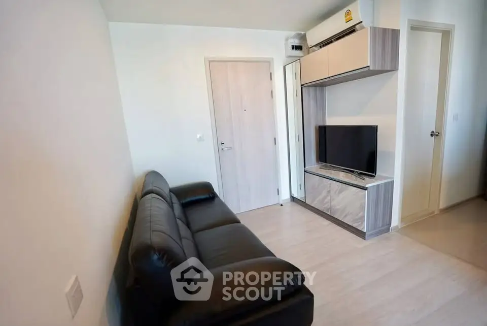 Modern living room with sleek black sofa and wall-mounted TV unit in a stylish apartment.