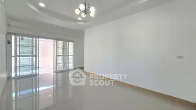 Spacious empty living room with glossy tiled floors and modern chandelier