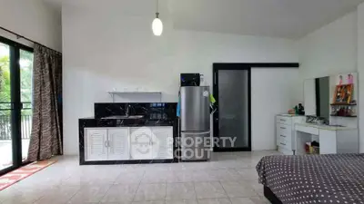 Spacious studio apartment with modern kitchenette and balcony access, perfect for urban living.