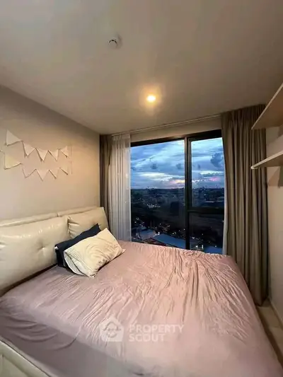 Cozy bedroom with city view and modern decor in high-rise apartment.