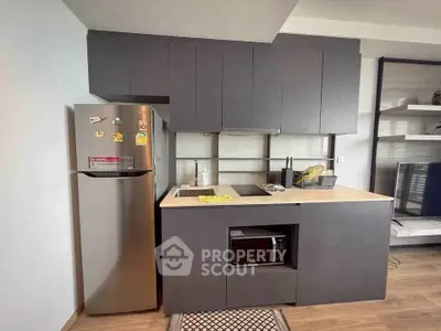 Modern kitchen with sleek cabinets and stainless steel fridge in compact layout.