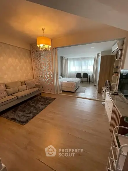 Spacious open-plan living room with elegant decor and cozy bedroom view, perfect for modern living.