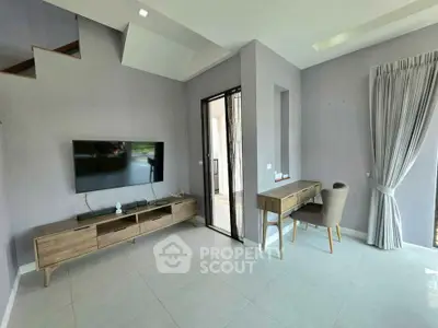 Modern living room with sleek furniture and natural light, featuring a wall-mounted TV and stylish desk area.