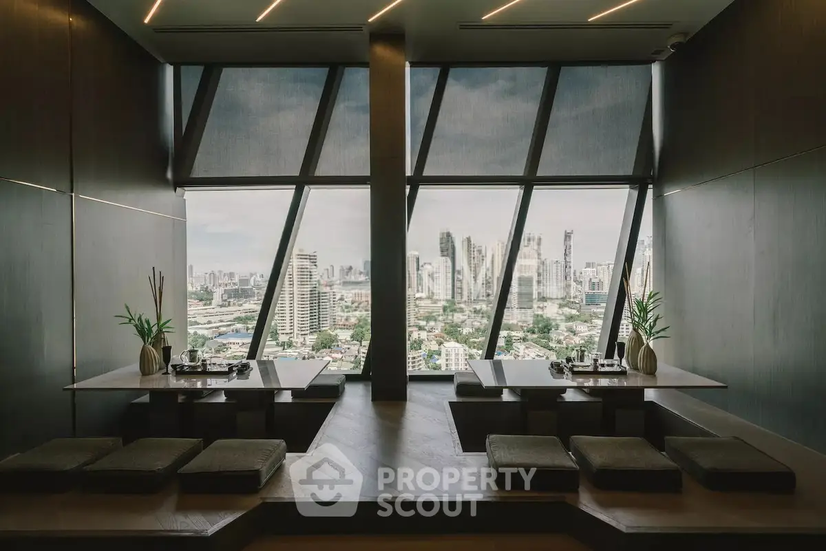 Luxurious dining area with panoramic city view and modern decor in high-rise building.