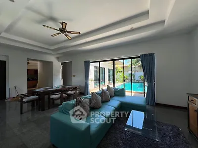 Spacious living room with pool view, modern furniture, and elegant ceiling fan in luxury home.