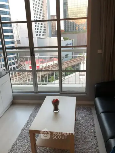 Modern living room with city view and balcony access in high-rise apartment.