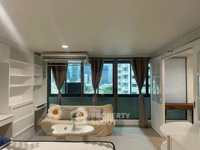 Modern living room with large windows and city view, featuring cozy sofa and stylish decor.