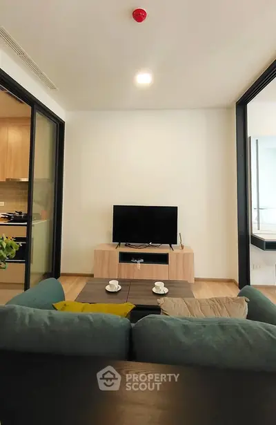 Modern living room with cozy sofa and TV, open layout to kitchen, ideal for urban living.