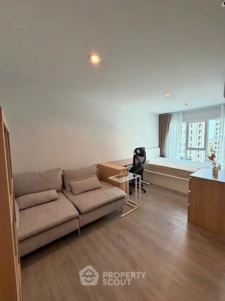 Modern studio apartment with cozy living area and large window view.