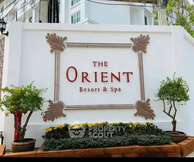 Elegant entrance sign of The Orient Resort & Spa with lush greenery.