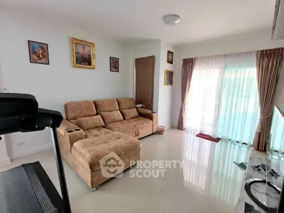 Spacious living room with cozy sofa and natural light from large windows.