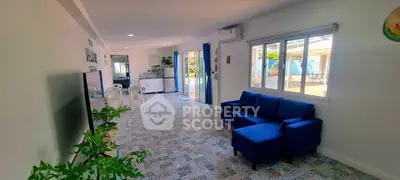 Spacious living room with blue sofa and patterned tile flooring, featuring large windows and open layout.