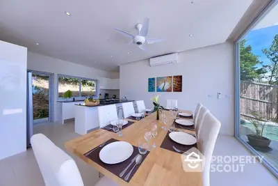 Modern dining area with open kitchen and large windows offering natural light