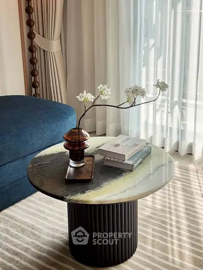 Stylish living room with elegant round table and plush blue sofa, perfect for modern interiors.