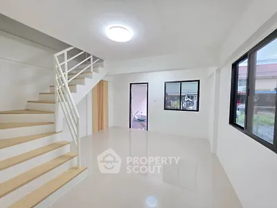 Spacious modern living room with staircase and large windows in a bright, minimalist home.