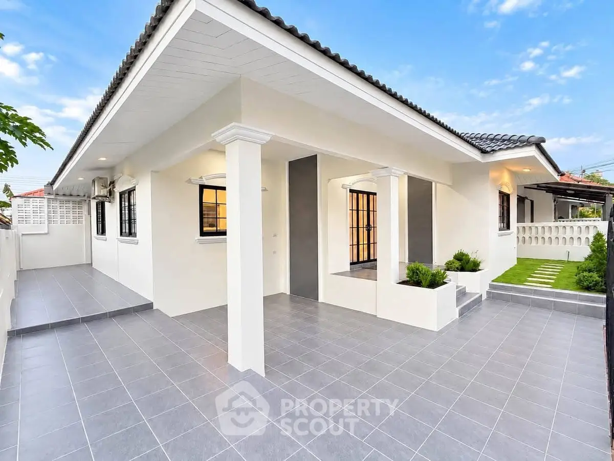 Charming single-story home with modern exterior and spacious tiled patio, perfect for outdoor living.
