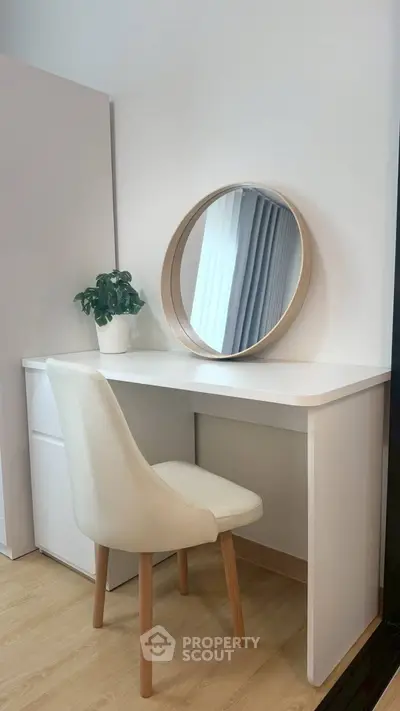 Modern study nook with white desk, round mirror, and elegant chair in a bright interior.