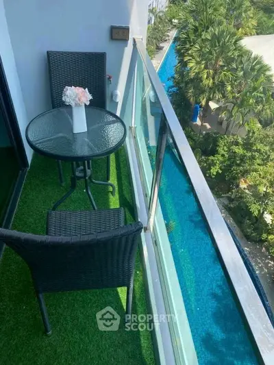 Charming balcony with pool view, featuring cozy seating and lush greenery, perfect for relaxation.