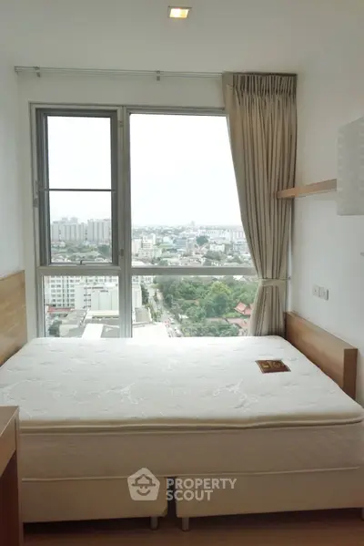 Bright bedroom with large window offering stunning city view in modern apartment.