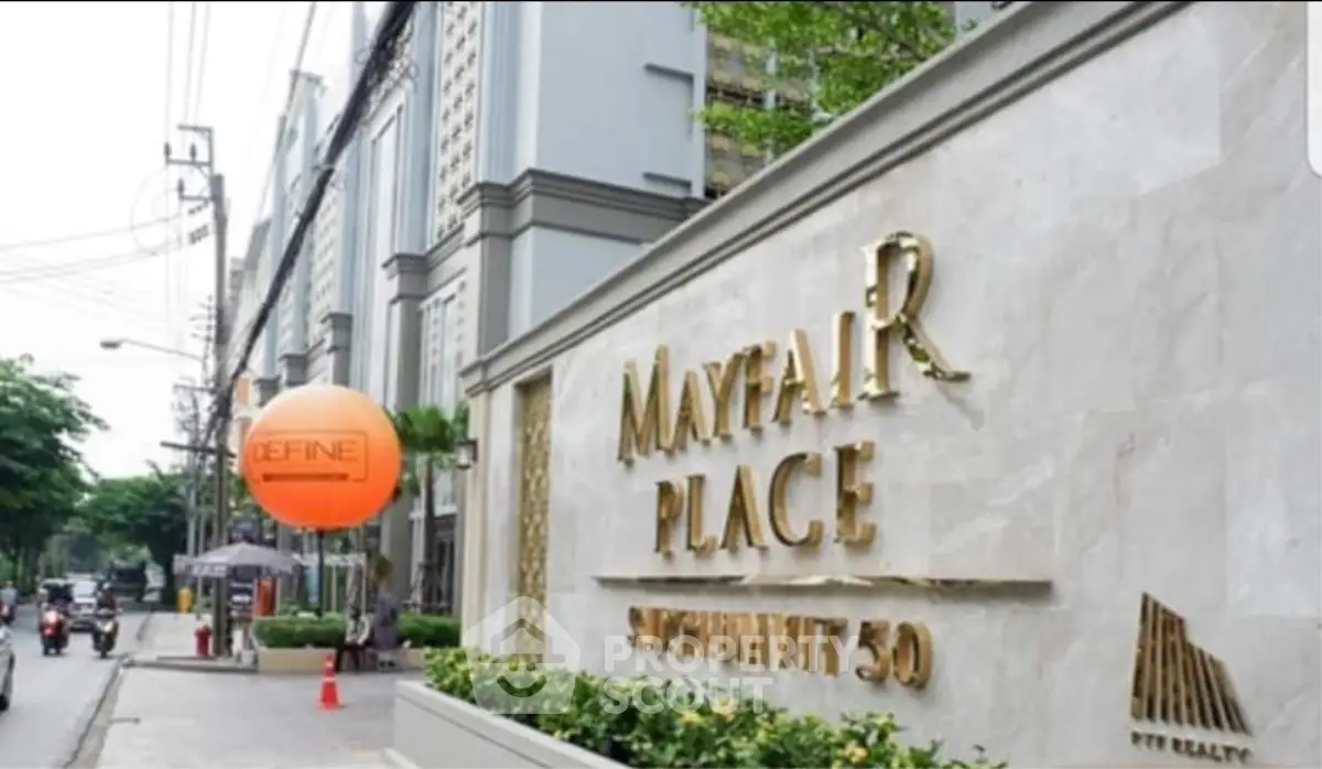 Elegant entrance of Mayfair Place Sukhumvit 50 with modern architecture and lush greenery.