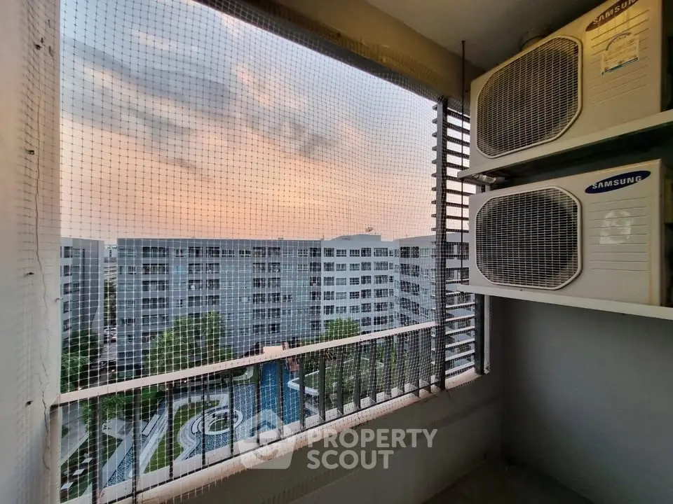 High-rise apartment view with air conditioning units and pool area at sunset.