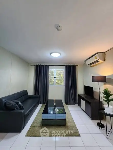 Modern living room with sleek black sofa, stylish coffee table, and large window with curtains.