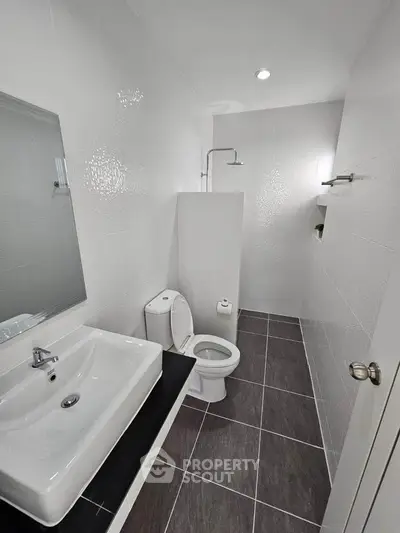 Modern minimalist bathroom with sleek fixtures and white tiles.