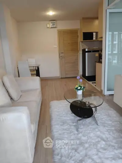 Modern living room with cozy sofa, glass coffee table, and open kitchen in stylish apartment.