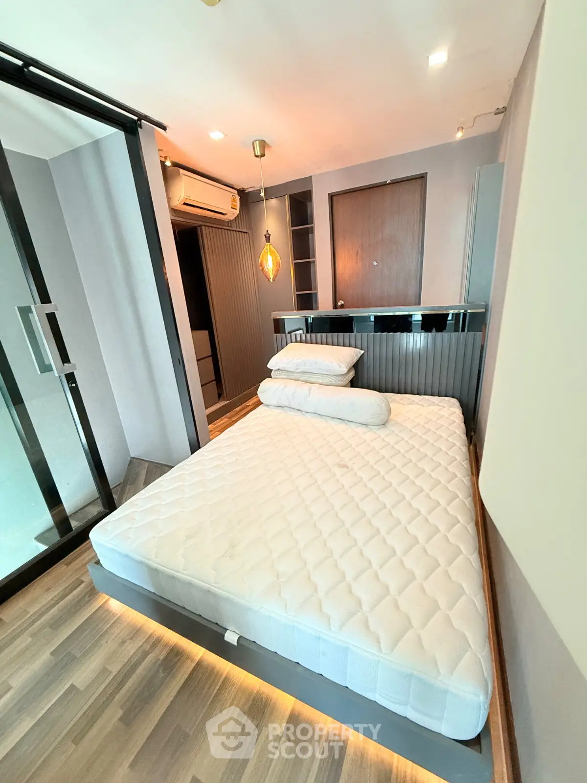 Modern bedroom with stylish lighting and sleek design, featuring a comfortable bed and wooden flooring.