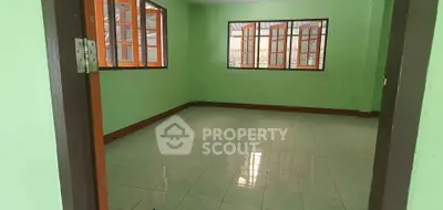 Spacious room with green walls and large windows offering ample natural light.