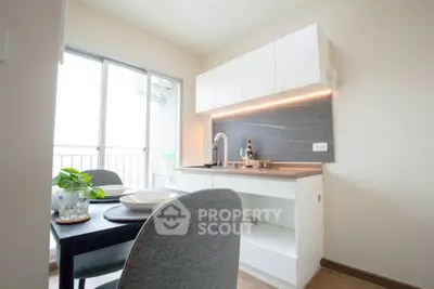 Modern kitchen with sleek design and open layout, featuring a dining area and balcony access.